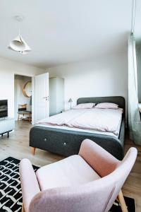 a bedroom with a large bed and two chairs at Gdynia Square Apartment in Gdynia