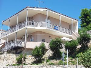 a large white building with a balcony and palm trees at Afytos Dream suites sea view in Afitos
