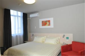 1 dormitorio con 1 cama y 1 silla roja en Jinjiang Inn - Economic Development Wujiang, en Suzhou