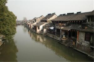 een rivier met huizen en gebouwen naast een rivier bij Jinjiang Inn - Economic Development Wujiang in Suzhou