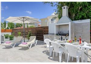 a patio with a table and chairs and an umbrella at Villa Coral in Peyia