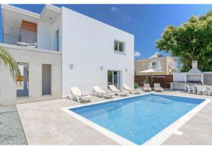a villa with a swimming pool in front of a house at Villa Coral in Peyia