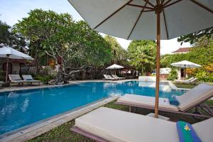 a swimming pool with lounge chairs and an umbrella at Natah Bale Villas in Sanur