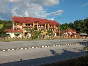 um edifício com um telhado vermelho no lado de uma estrada em Arjuwani Homestay Gua Musang em Gua Musang