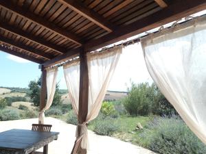 un patio con cortinas blancas y una mesa de madera en Poggio delle Lavande, en Montelupone