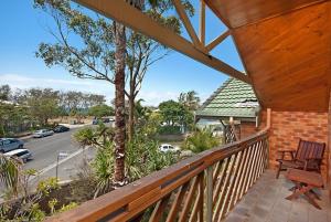 a wooden railing on a porch with a view of a street at Byron Bay Accom - Balcony on Lawson in Byron Bay