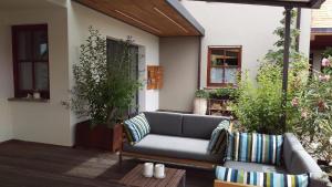 une terrasse couverte avec un canapé et des chaises. dans l'établissement Ferienwohnungen Familie Neubert, à Nordheim