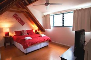 a bedroom with a red bed and a window at Byron Bay Accom Unit 3 41 Childe Street - Belongil Beach Apartment in Byron Bay