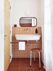a bathroom with a sink and a stool at Hôtel Voltaire in Arles