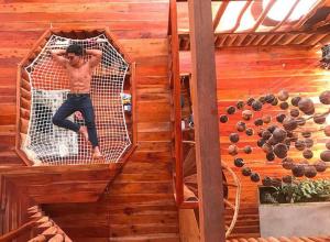 un hombre tendido en una red en una cabaña de madera en Camiguin Volcano Houses - A-Frame house, en Mambajao