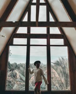 una persona parada frente a una gran ventana en Camiguin Volcano Houses - A-Frame house, en Mambajao