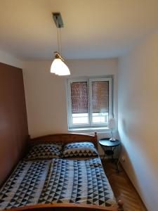 a bedroom with a bed and a lamp and two windows at ALEX Apartman in Sopron