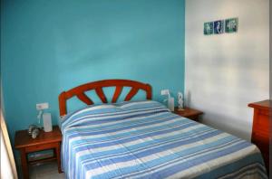 ein blaues Schlafzimmer mit einem Bett mit gestreifter Decke in der Unterkunft Casa el mar in Costa Teguise