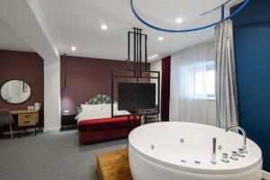 ein Badezimmer mit einer Badewanne und ein Schlafzimmer mit einem Bett in der Unterkunft Hotel Bohemian Garni - Skadarlija in Belgrad