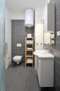 ein Badezimmer mit Waschbecken, Toilette und Spiegel in der Unterkunft Apartments Alluro in Rovinj