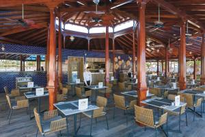 un restaurante con mesas y sillas y un hombre de pie en el fondo en Hotel Riu Palace Tenerife, en Adeje