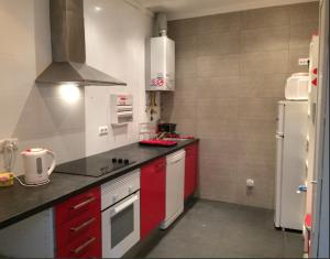 a kitchen with red cabinets and a white refrigerator at Green Wave Hostel in Figueira da Foz