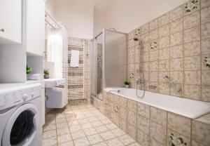 a bathroom with a tub and a washing machine at Apartment Enenkelstrasse in Vienna