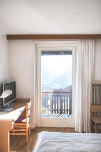 a bedroom with a desk and a window with a view at Hotel Gasthof Stern in Nova Ponente
