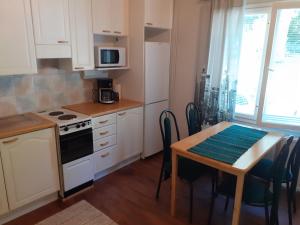 uma cozinha com armários brancos e uma mesa com um fogão em huoneisto 2 em Savonlinna