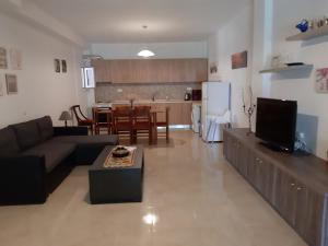 a living room with a couch and a table and a kitchen at Maria Lemoni swimming pool apartment in Nea Skioni