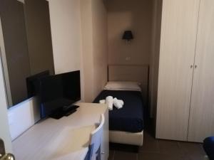 a small room with a bed and a desk with a television at Hotel Alabama in Riccione