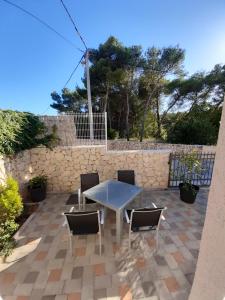 un patio con mesa, sillas y pared de piedra. en Holiday Home Don en Zadar