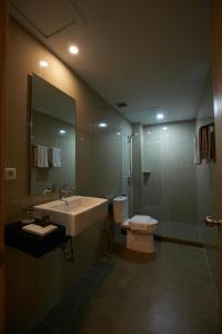 a bathroom with a sink and a toilet and a mirror at Winstar Hotel in Pekanbaru