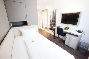 Schlafzimmer mit einem Bett, einem Schreibtisch und einem TV in der Unterkunft Manhattan Hotel in Frankfurt am Main
