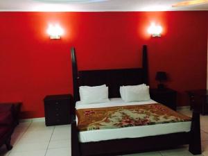 a bedroom with a bed with a red wall at Royal Guest House Lahore Cantt in Lahore