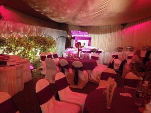 a room with tables and chairs and a stage with pink lighting at Royal Guest House Lahore Cantt in Lahore