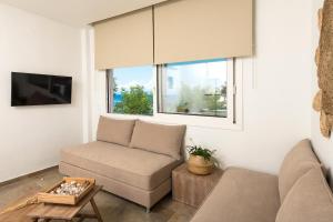 a living room with a couch and a tv at Konstantinou Deluxe Apartments in Skala Marion