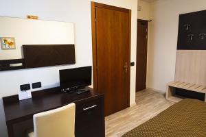 um quarto com uma secretária, uma televisão e uma cama em B&B Villalta em Treviso