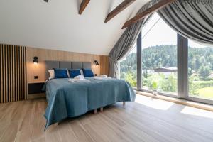 a bedroom with a bed and a large window at Apartamenty Marron z sauną, bawialnią i widokiem na Skrzyczne - Dream Apart in Szczyrk