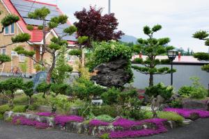 HDO Furano Garden House في فورانو: حديقة فيها ورد واشجار في ساحة