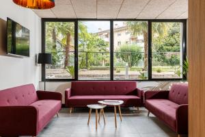 uma sala de espera com dois sofás vermelhos e uma mesa em Arco Smart Hotel em Arco