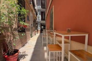 uma fila de mesas e bancos do lado de um edifício em Feel Hostels City Center em Málaga