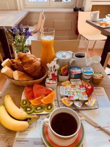 uma mesa coberta com alimentos de pequeno-almoço e uma chávena de café em Hôtel De La Cathédrale em Reims