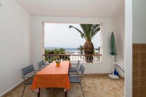 a dining room with a table and chairs and a palm tree at Apartments Milana in Tučepi