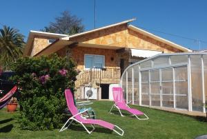 奧萊羅斯的住宿－O Arrequento，房子的院子内有两把粉红色的椅子