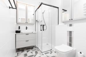 La salle de bains blanche est pourvue d'une douche et de toilettes. dans l'établissement Apartamenty Rajska 8 - Gdańsk Stare Miasto by Renters, à Gdańsk