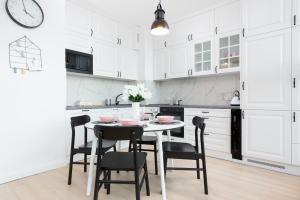 - une cuisine blanche avec une table et des chaises noires dans l'établissement Apartamenty Rajska 8 - Gdańsk Stare Miasto by Renters, à Gdańsk