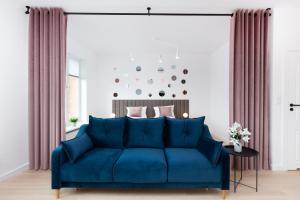 - un canapé bleu dans le salon avec des rideaux dans l'établissement Apartamenty Rajska 8 - Gdańsk Stare Miasto by Renters, à Gdańsk
