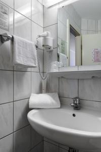 La salle de bains blanche est pourvue d'un lavabo et d'un miroir. dans l'établissement Motel Drei König- Ihr Transithotel, à Heimsheim