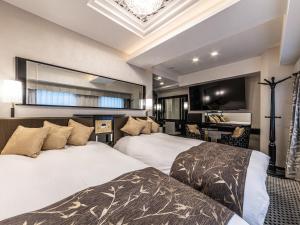 a hotel room with two beds and a flat screen tv at APA Hotel Roppongi SIX in Tokyo