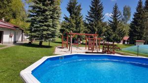 una gran piscina con un parque infantil y un columpio en Chaty U Skály Kytlice en Kytlice