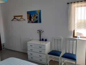 a bedroom with a white dresser and two chairs at Vivenda Familia Pedro in Vila do Bispo