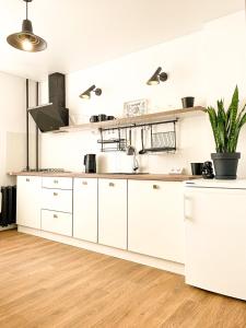 a kitchen with white cabinets and a wooden floor at Birdie Home at Nauky metro in Kharkiv