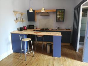una cocina con una isla azul con taburetes de bar en STUDIO INDEPENDANT DANS FERME 18ème en Saint-Michel-sur-Savasse