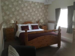 a bedroom with a wooden bed and a window at Grove House Guest House in Telford